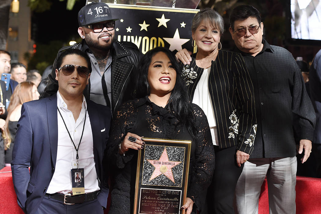 Suzette Quintanilla, del centro, hermana de la fallecida cantante Selena Quintanilla, sostiene una réplica de su nueva estrella en el Paseo de la Fama de Hollywood mientras posa con, desde la izq ...