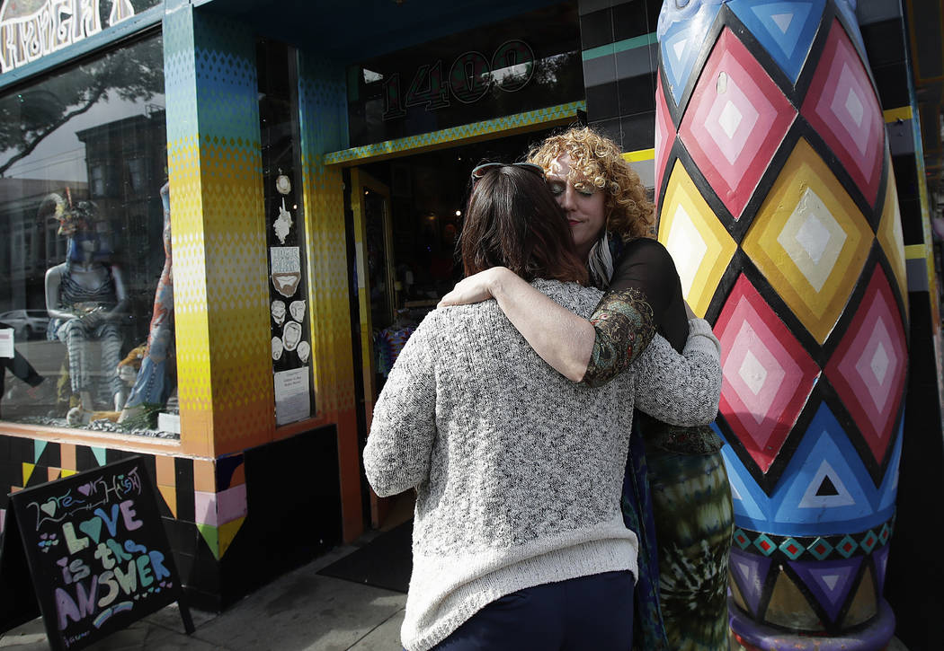 Sunshine Powers, dueño de la tienda Love on Haight, a la derecha, abraza a Christin Evans, dueña de The Booksmith, afuera de la tienda de Powers en San Francisco, el 1 de octubre de 2018. (AP Ph ...