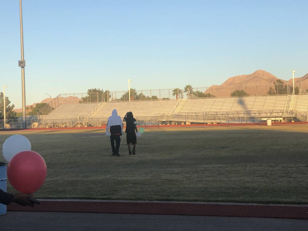 Los hijos de Susan Nash, De'Angelo y De'Andre Nash, a la derecha, caminan hacia el centro del campo de fútbol de Desert Pines High School, donde se pintó un corazón con las iniciales de su madr ...
