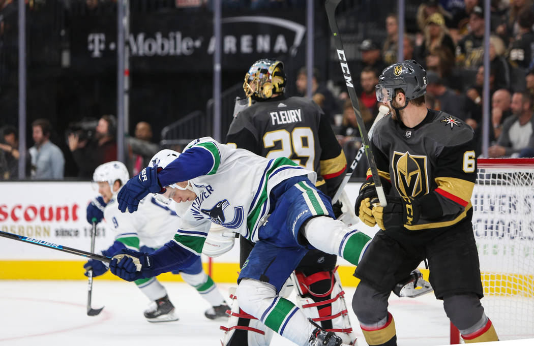 El centro de los Canucks de Vancouver, Bo Horvat (53), es derribado por el defensa Colin Miller (6) de los Golden Knights durante el segundo período de un juego de hockey de la NHL en T-Mobile Ar ...