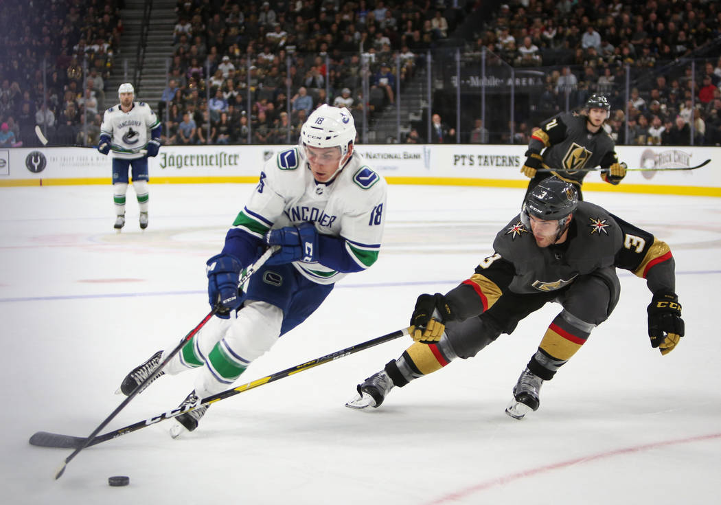 El defensa Brayden McNabb (3) de los Golden Knights alcanza el puck contra el alero derecho de Vancouver Canucks, Jake Virtanen (18), durante el segundo período de un juego de hockey de la NHL en ...