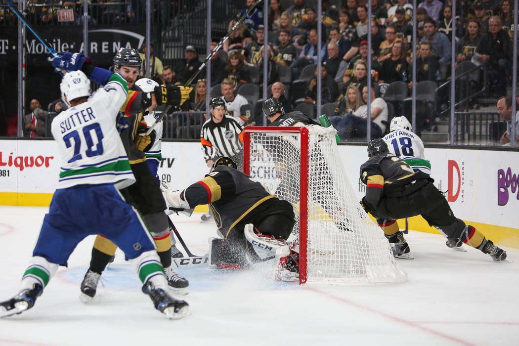 El alero derecho de Vancouver Canucks, Jake Virtanen (18), se lleva el puck detrás del gol de los Golden Knights durante el segundo período de un juego de hockey de la NHL en T-Mobile Arena en L ...