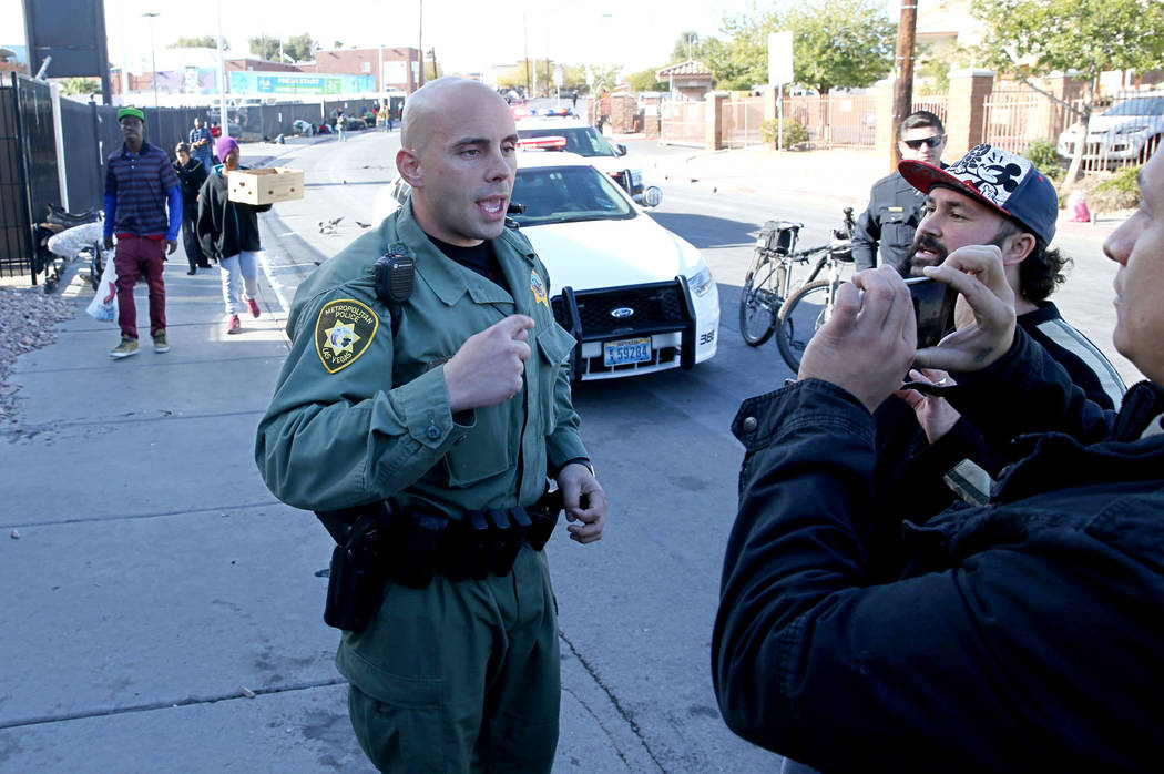 Un oficial de la policía de Las Vegas discute con Joey Lankowski, segundo a la derecha, y Joshua Martinezm donde Lankowski estaba distribuyendo comida en Foremaster Lane, cerca de Las Vegas Boule ...