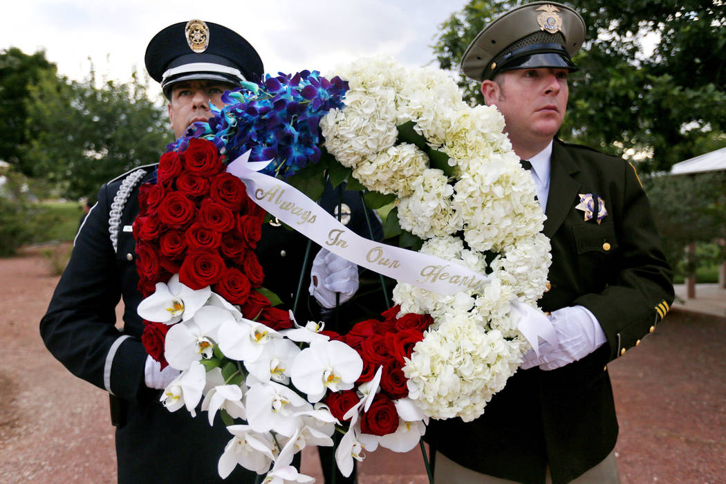 Los oficiales sostienen flores para el servicio conmemorativo de los oficiales de policía del ...