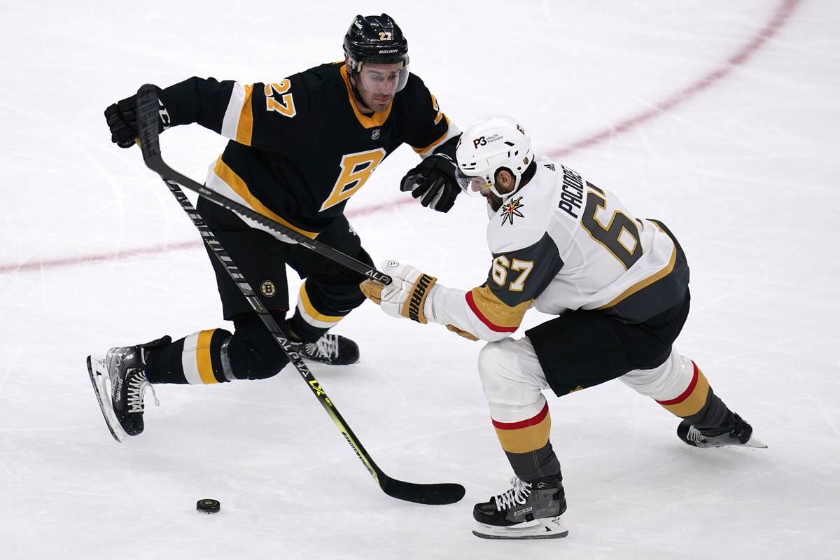 El defensa de los Boston Bruins John Moore (27) controla al ala izquierda de los Vegas Golden K ...