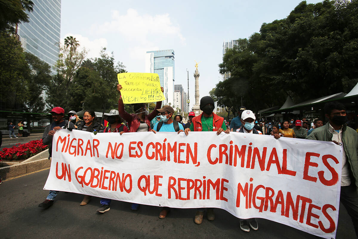 Migrantes sostienen un cartel que dice: "Migrar no es un crimen, criminal es un gobierno que re ...