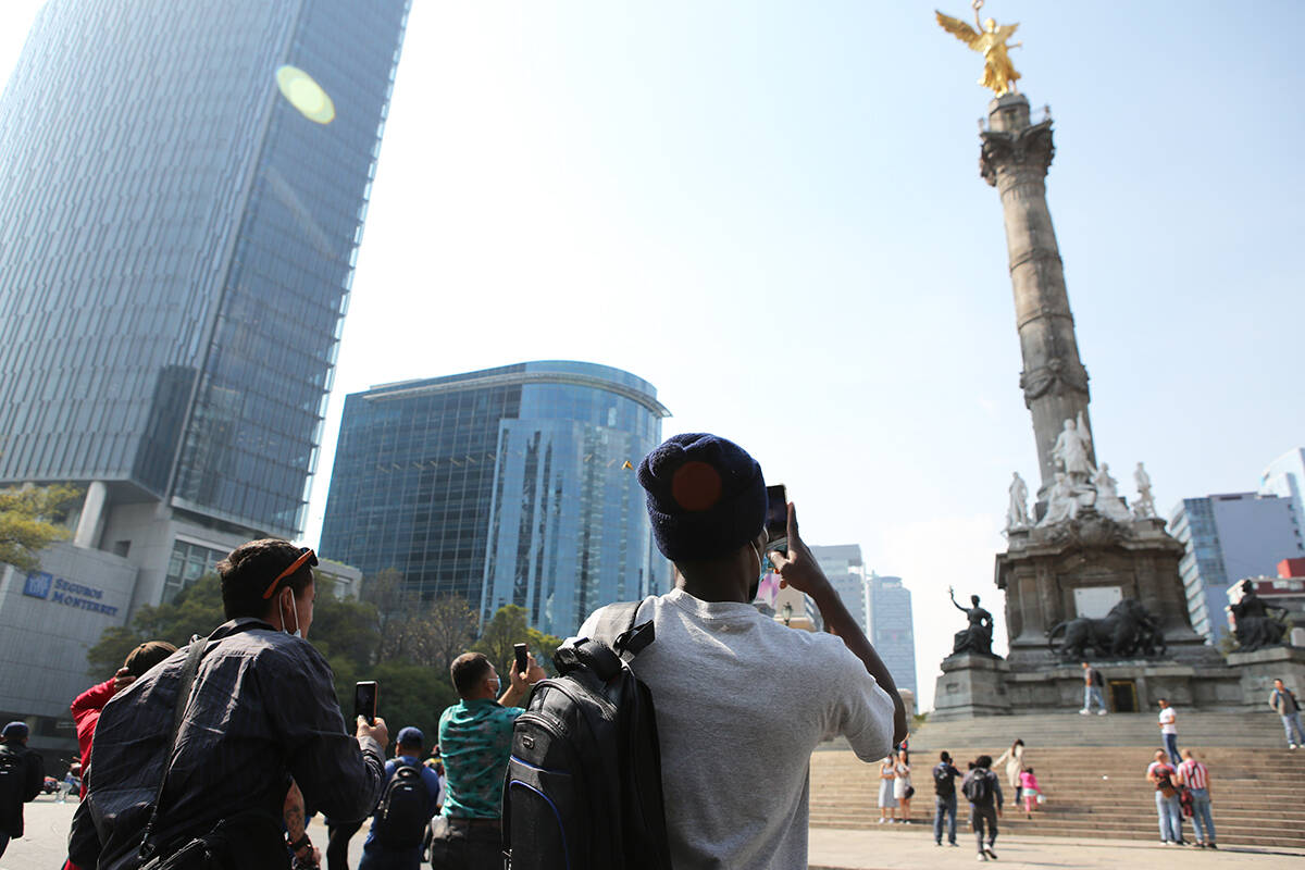 Migrantes toman fotos de "El Ángel de la Independencia" en la Ciudad de México, el sábado 18 ...