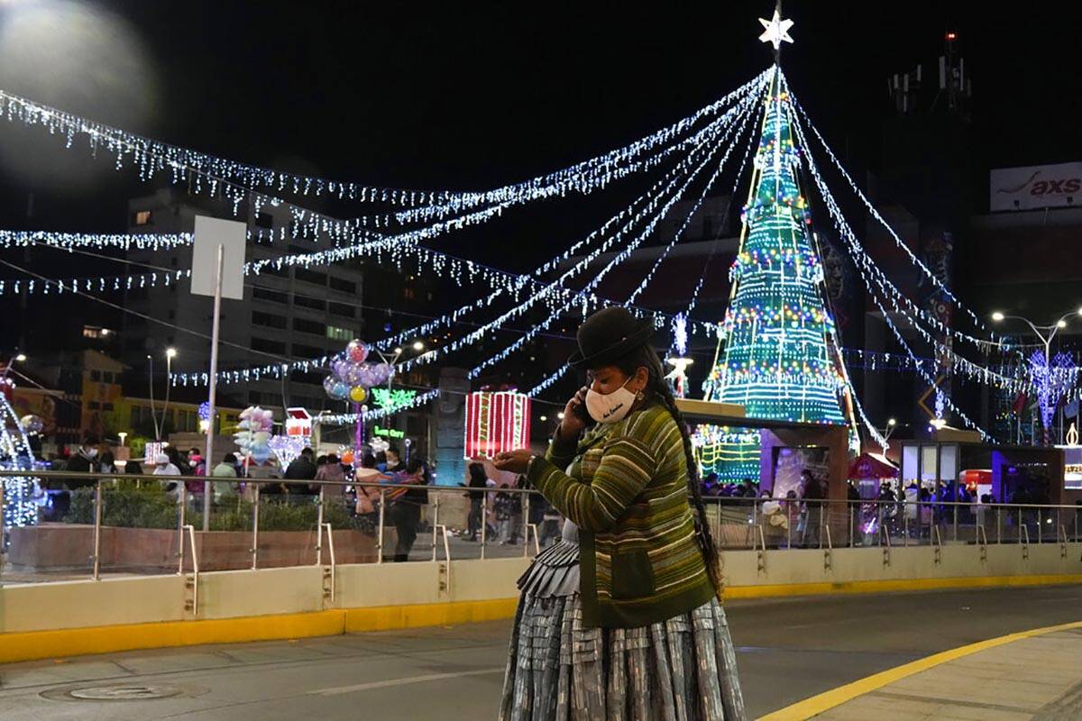 Una mujer aymara habla por su teléfono en la plaza Tejada Sorzano adornada con luces navideña ...