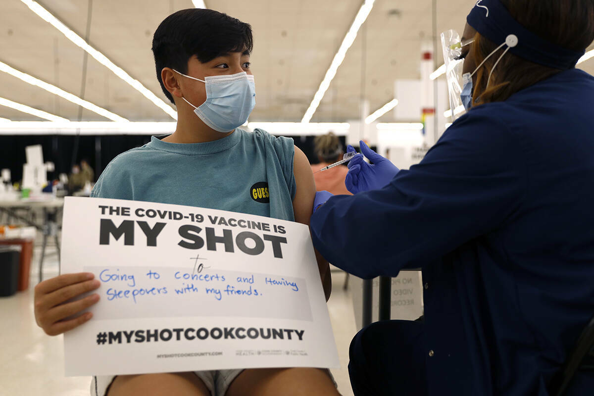 Lucas Kittikamron-Mora, de 13 años, sostiene un cartel en apoyo de las vacunas contra COVID-19 ...